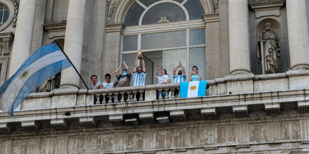 Fans waving Argentina football flags, showing team spirit during a celebration.