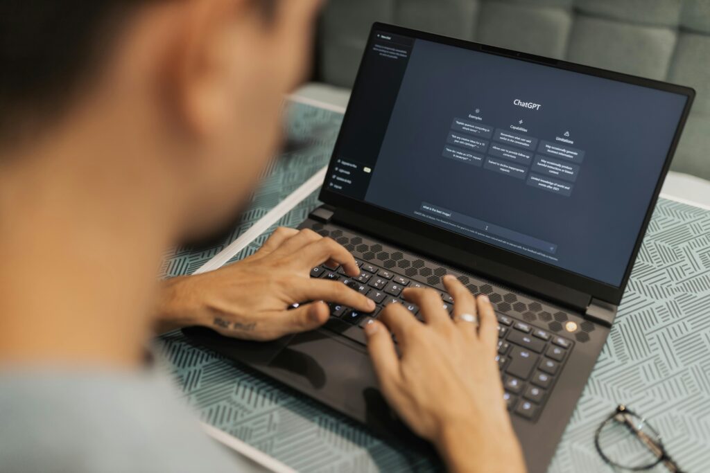 A person typing on a laptop with an AI interface on the screen, representing the use of an AI detector. The image highlights the interaction with AI technology and the importance of AI detectors in ensuring accuracy and understanding in AI-generated content.