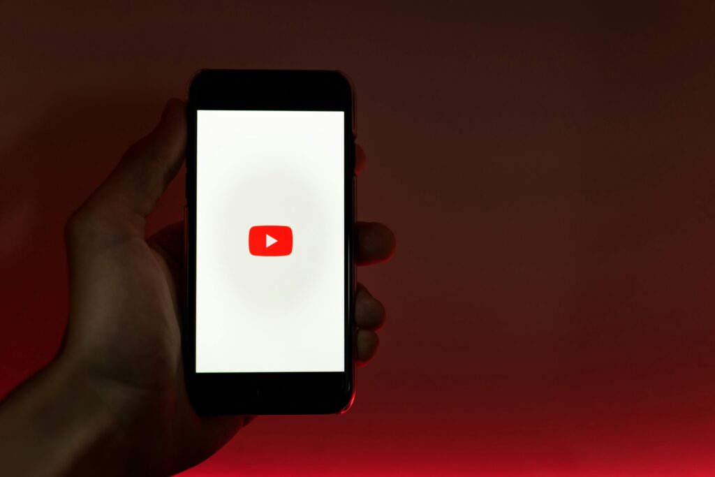 Hand holding smartphone with YouTube downloader logo on screen